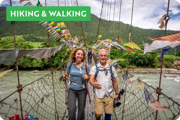 Two people walking on a wooden bridge over a river