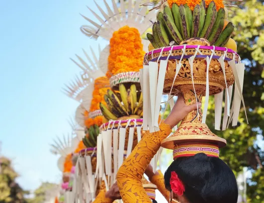 Procession of beautiful Balinese women in traditional costumes - sarong, carry offering on heads for Hindu ceremony.