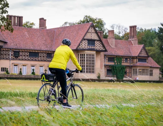 Person wearing a yellow jacket, riding a bike with a large building in the background