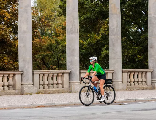 Woman in a green shirt, riding a bike on a road