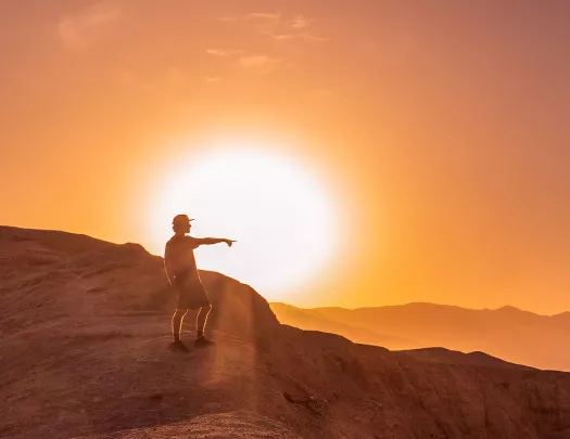 Person standing on a cliff with the sunset in the background