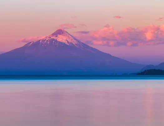 Mountain with a large lake in front and pink skies