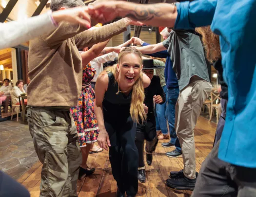 Woman walking under a group of people with their arms sticking out