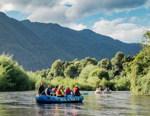 Group of people on a blue raft, paddling in the middle of a river