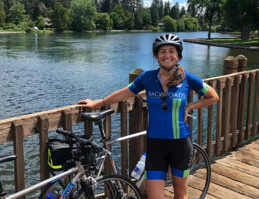 Guest posing on wooden bridge, lake or river in background.