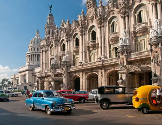 Exterior view of large palace building with old school cars in front