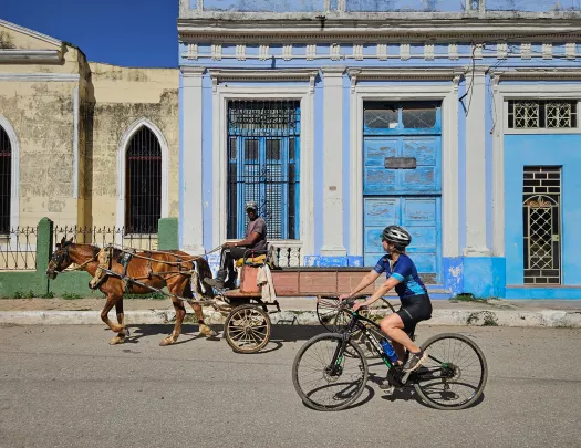 Woman riding a bike while looking at a man on a horse carriage