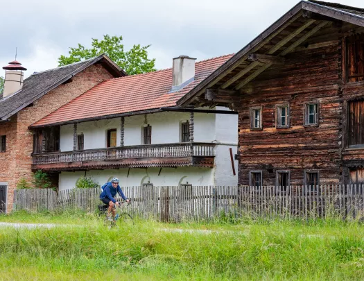 Man riding a bike on an empty road with wooden houses in the background