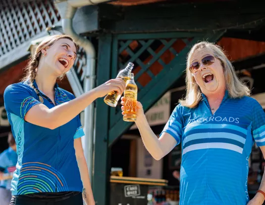 Two woman clinking their bottles of drinks and smiling