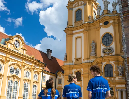 Three bikers posing together in front of the Melk Abbey.