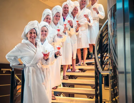 Backroads guests lined up in a row on a set of stair, all in white robes and towels on heads.