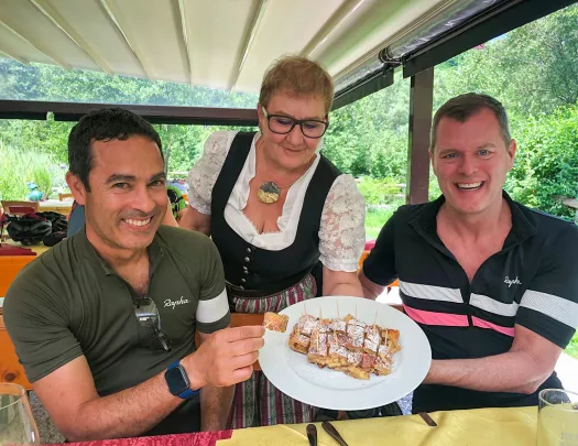 Waiter holding plate of cake for two guests.