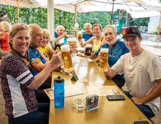 Guests sitting around a table holding pints of beer.
