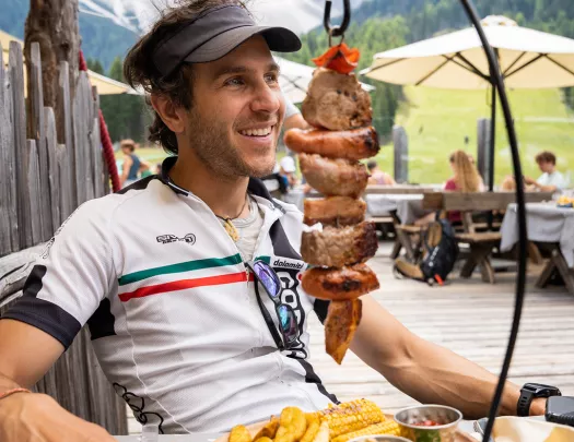 Guest/leader at meal, hanging shish kabob(?) with potato wedges in front of them.