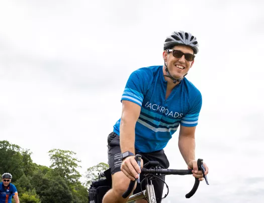 Ground-level shot of guest cycling, smiling at camera.