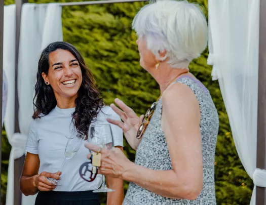 Two women smiling and talking, while holding glasses of wine