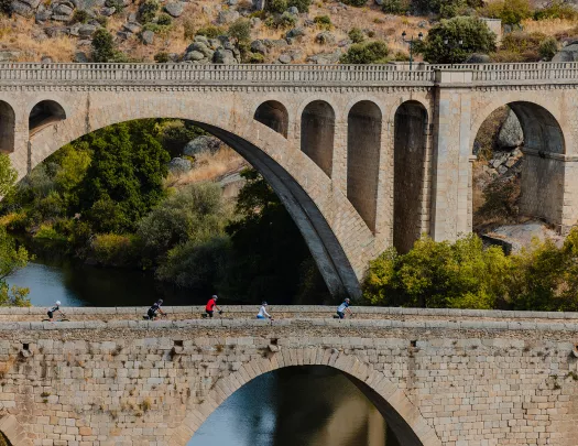Group of people biking on a stone bridge