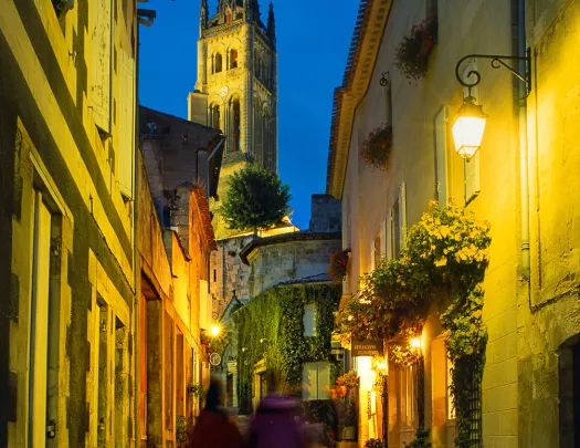 Two guests walking down French alleyway, church spire in front of them.