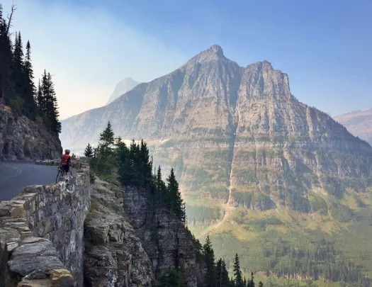Solo biker looking over a wall into a mounatin valley