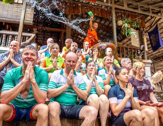a group of people get splashed with water in a ceremony outside a temple