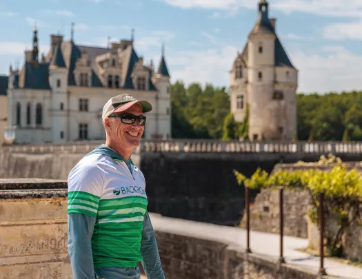 Guest smiling with green and white French chateau behind.