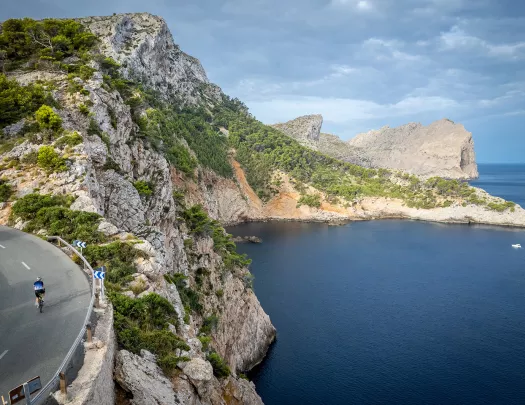 Biker riding around a bend on the coast of Mallorca.
