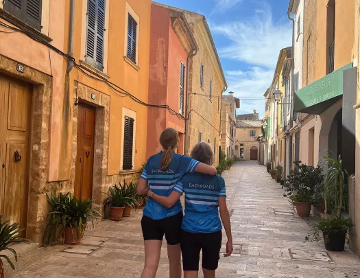 Two people hugging, walking down a cobblestone alley.