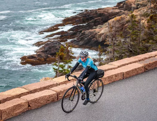 Guest biking on road, rough ocean water in background.