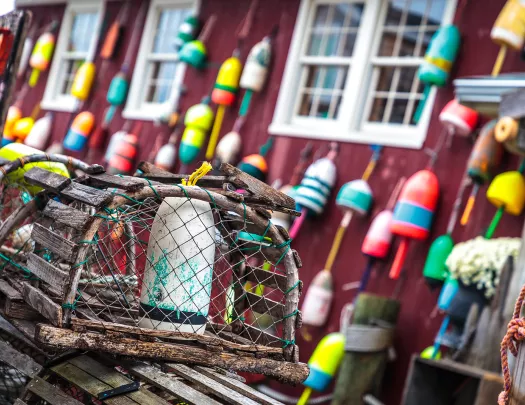 Shot of lobster trap in front of red fishing shack.