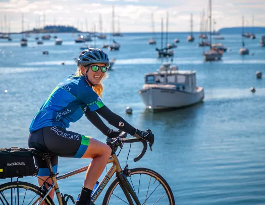 Guest biking with ocean and ships in background.