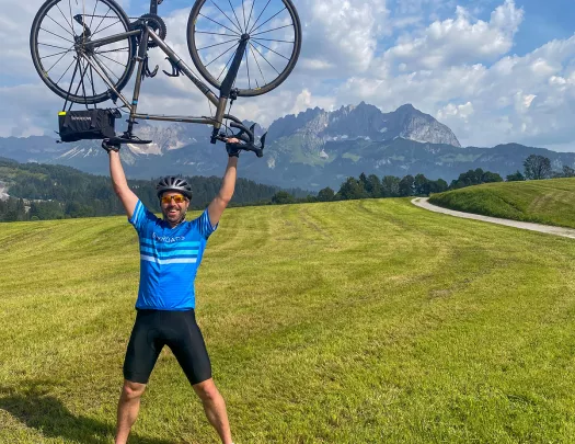 Man in a grassy field holding up a bike over his head