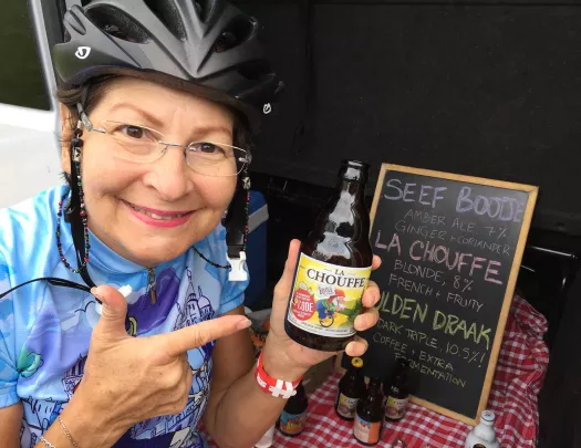 Guest in bike gear pointing to beer bottle in hand.