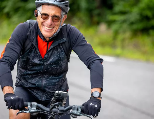 Older biker smiling while riding.