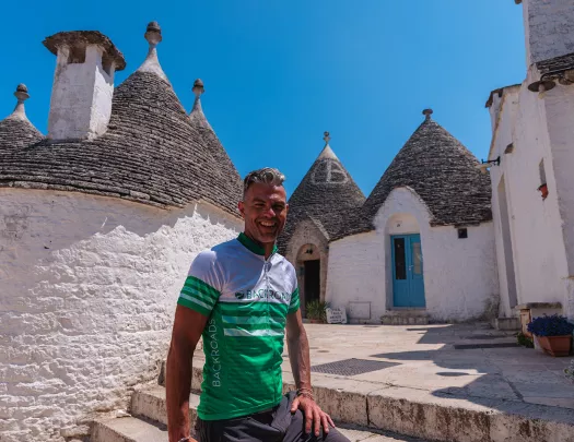 Guest smiling in front of Alberobello houses.