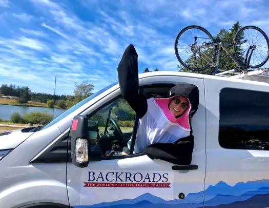 Leader in orca costume waving to camera in the front seat of BR van.