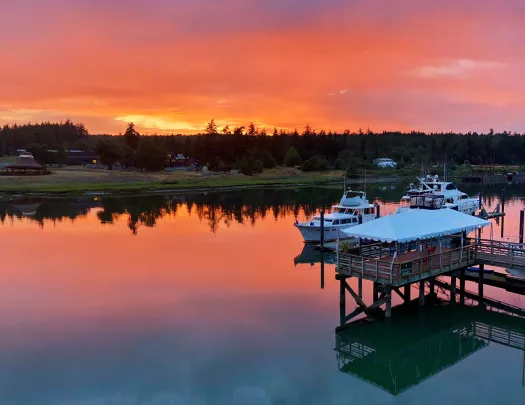 Shot of two ships at pier, sun setting in background.