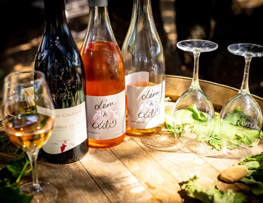Close-up of wine glasses, bottles on barrel.