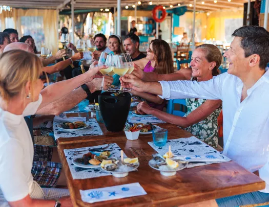 Guests at meal, cheersing wine glasses.