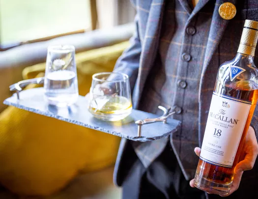 Man holding a bottle of whisky and two glasses