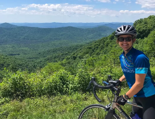 Guest smiling at camera, vast forest vista to her right.