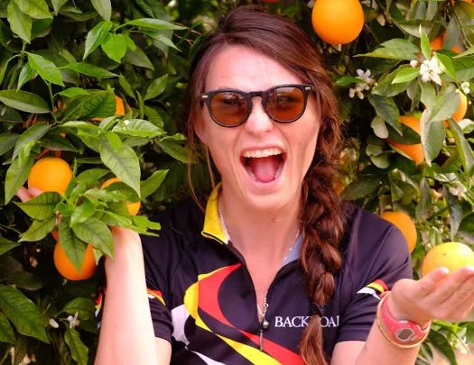 Guest/leader under an orange tree, smiling at camera.