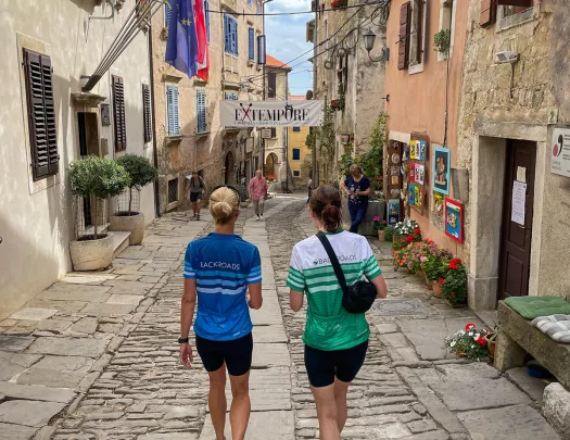 Two women walking in an alleyway surrounded by stone buildings