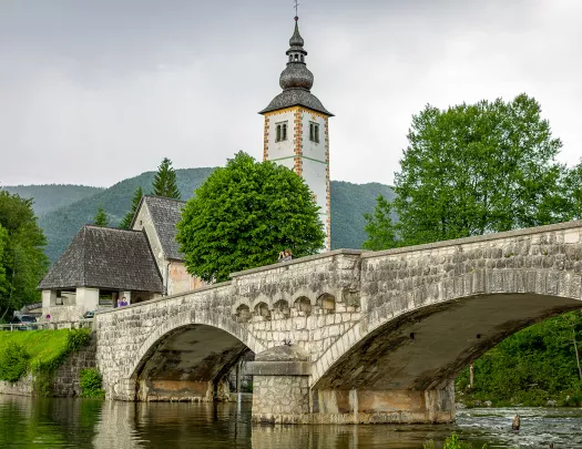 Stone bridge with a rustic bell tower in the background