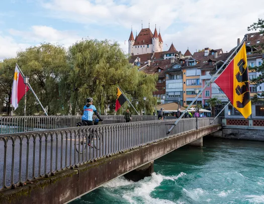 Woman biking across a bridge surrounded by large flags