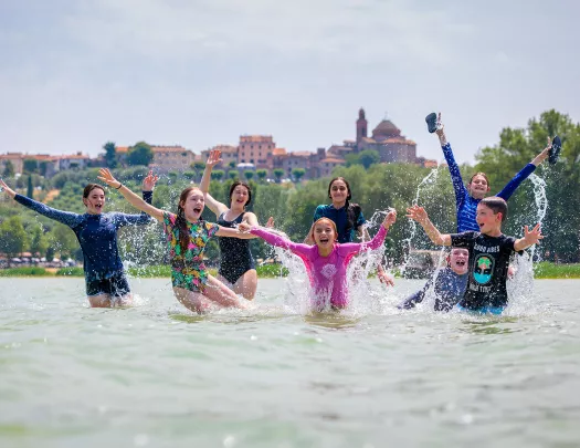 Group of kids in the ocean with their hands in the air