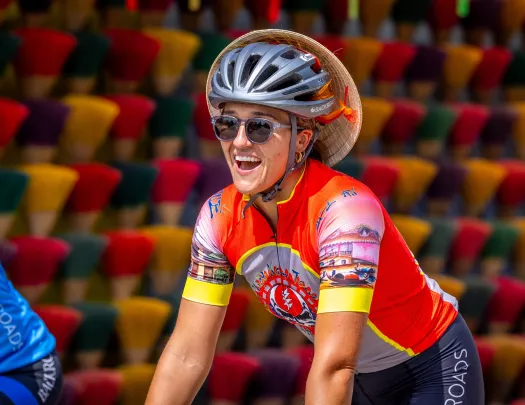 Woman smiling while riding a bike and wearing a helmet and sunglasses