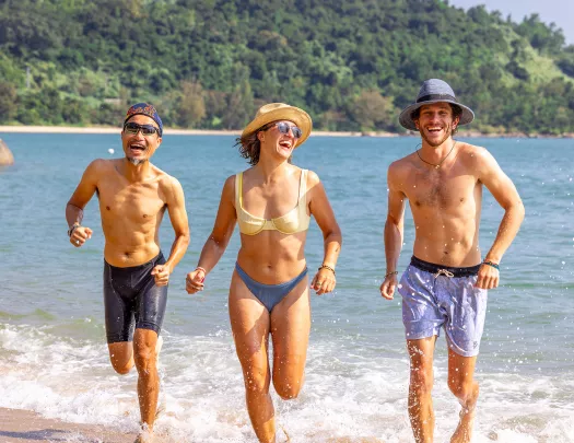 Three people running on the beach