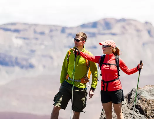 Man and woman with hiking poles, pointing and looking out to mountains