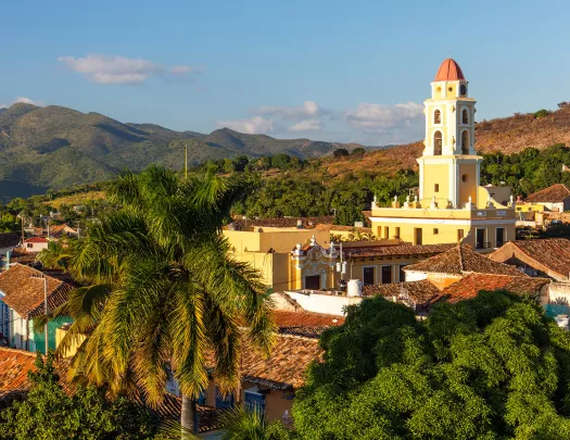Sky view of a yellow church in the distance, surrounded by trees