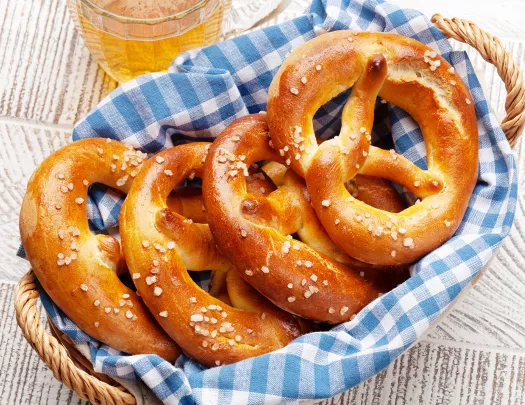 Lager beer mug and fresh baked homemade pretzel with sea salt on wooden table. Classic beer snack